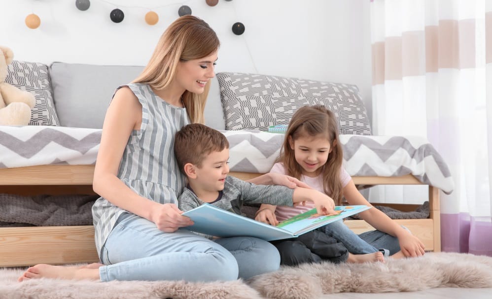 nanny reading book to little childrens at home