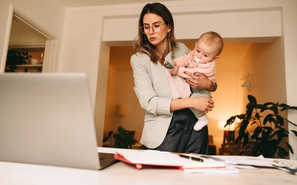 Professional interior designer holding her baby while working in her home office
