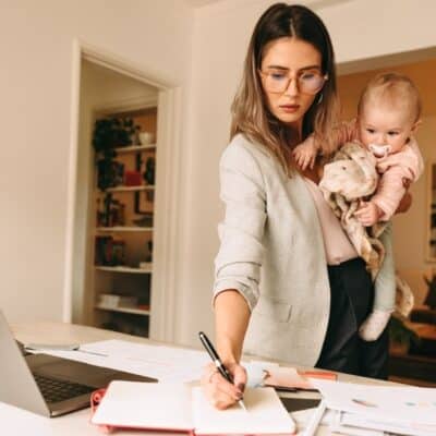female interior designer making notes while holding her baby